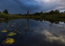 Cerkiew nad jeziorem pod zachmurzonym niebem