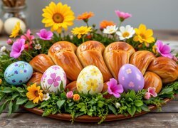 Chleb na talerzu otoczony kwiatami i pisankami