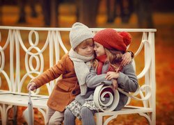 Chłopczyk przytula dziewczynkę na parkowej ławce