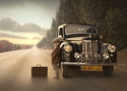 Chłopczyk z walizką stoi na drodze obok zabytkowego Forda