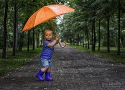 Chłopiec w gumowcach z parasolem