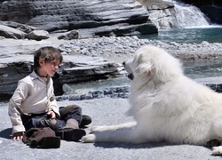 Chłopiec z psem nad rzeką w scenie z filmu Bella i Sebastian