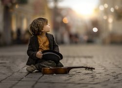 Chłopiec ze skrzypcami siedzący na ulicy