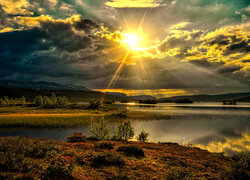Chmury i promienie słońca na niebie nad górami i jeziorem