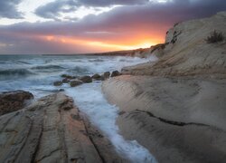Chmury i zachód słońca nad skalistym wybrzeżem morza
