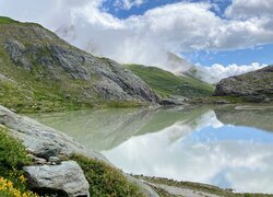 Chmury nad skalistymi górami i jeziorem