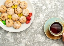 Ciasteczka i truskawki na talerzu obok filiżanki z herbatą