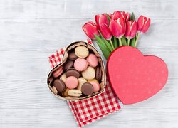 Ciasteczka w pudełku w kształcie serca obok czerwonych tulipanów