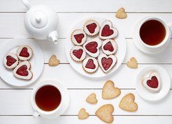 Ciastka w kształcie serc na talerzykach i filiżanki z herbatą
