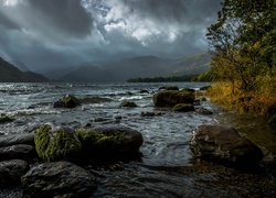 Ciemne chmury nad kamienistą rzeką w górach