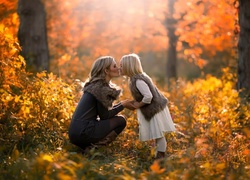 Córka daje buziaka mamie podczas jesiennego spaceru w lesie