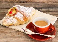 Croissant obok czerwonej filiżanki z kawą