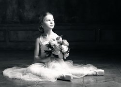Czarno-białe zdjęcie małej baletnicy z bukietem kwiatów