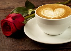 Czerwona róża obok filiżanki z cappuccino
