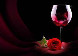 Czerwona róża obok kieliszka z winem