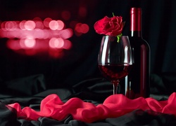 Czerwona róża w kieliszku obok butelki z winem