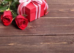 Czerwone róże obok prezentu na deskach
