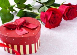 Czerwone róże obok pudełka w kształcie serca