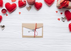 Czerwone serca ułożone na deskach obok prezentu świeczek i listu