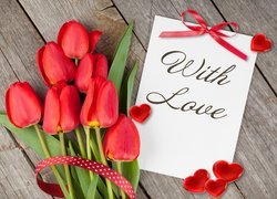 Czerwone tulipany obok kartki z napisem With love i serduszek