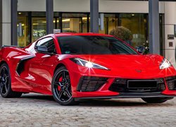 Czerwony Chevrolet Corvette Stingray przed budynkiem