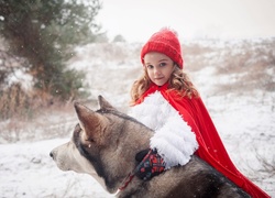 Czerwony Kapturek z psem siberian husky w zimowej scenerii