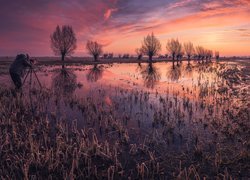 Człowiek fotografujący rozlewisko o zachodzie słońca