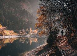 Człowiek na ścieżce pod jesiennymi drzewami nad rzeką w górach