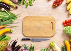 Deska i nóż pośród warzyw i owoców