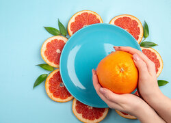 Dłonie trzymające pomarańczę nad talerzem