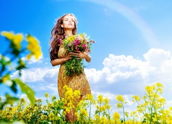 Długowłosa dziewczyna w zwiewnej sukience z bukietem kwiatów