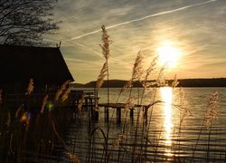 Dom na pomoście nad jeziorem o zachodzie słońca