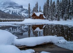 Dom w śniegu nad jeziorem Emerald Lake i mgła nad Górami Skalistymi