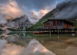 Domek na pomoście na jeziorze Pragser Wildsee w zamglonych Dolomitach