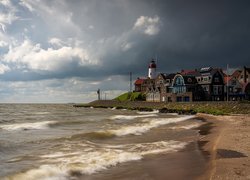 Domy i latarnia morska na brzegu jeziora IJsselmeer