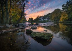 Domy pod jesiennymi drzewami nad rzeką