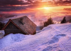 Drewniana chata na tle wschodu słońca zimą