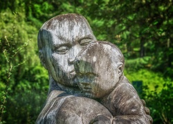 Drewniana rzeźba przedstawiająca ojca przytulającego dziecko