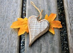 Drewniana zawieszka w kształcie serca na jesiennych liściach