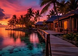 Drewniane domki i palmy nad morzem o zachodzie słońca