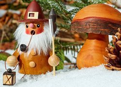 Drewniany dziadek z grzybem i szyszką w śniegu