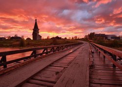 Drewniany most z widokiem na cerkiew o zachodzie słońca