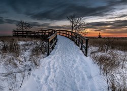 Drewniany mostek o zachodzie słońca zimą