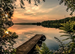 Drewniany pomost nad jeziorem o wschodzie słońca