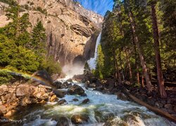 Drzewa i tęcza na skałach nad rzeką w Parku Narodowym Yosemite