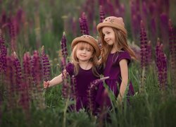 Dwie dziewczynki w kapeluszach wśród łubinów