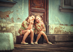 Dwie dziewczynki z lizakami - kogucikami przed domem