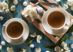 Dwie filiżanki herbaty pośród kwiatów jaśminowca