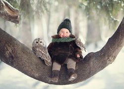 Dziecko i sowy na konarze drzewa