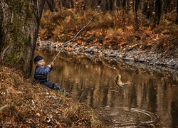 Dziecko nad rzeką z rybą na haczyku